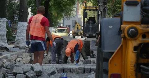 Workers in Orange Workwear Are Paving The Road at City Street Road Repair Stock Footage 54329409