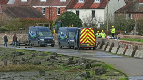 Workers outside in hard hats, doing electrical work with vans nearby, UK Stock Footage 237590714