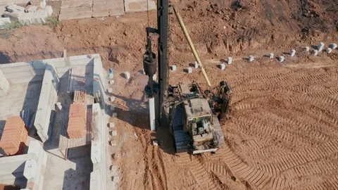 Workers in overalls and helmets install concrete pillars with the help of Stock Footage 157925142