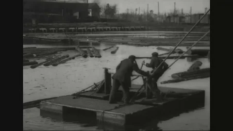 Workers pass soaked logs to the mill via log chain conveyor - 1918 Stock Footage 83663442