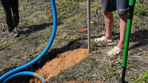 Workers perform soil testing at a construction site in a rural area during a sun Stock Footage 336158366