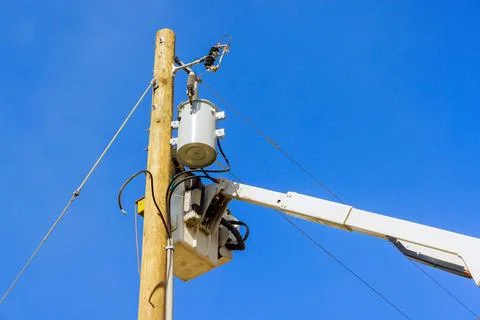 Workers performing maintenance on an electrical transformer atop utility pole Stock Photos