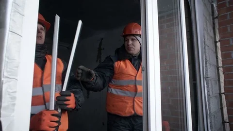 Workers place the glass in the plastic frame of the window Stock Footage 82303069