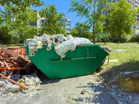 Workers placed large amounts of construction waste in a green dumpster by the Stock Photos