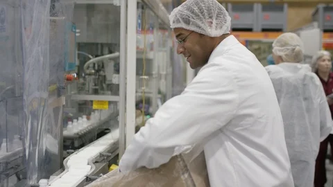 Workers placing empty cosmetic bottles on conveyor belt on production line Stock Footage 107954666