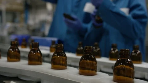 Workers placing inspected bottles on production line in cosmetic factory Stock Footage 107952835