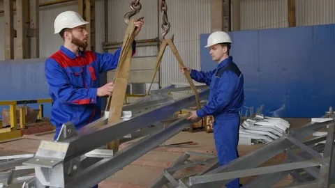 Workers at the plant load the cargo onto the hook of the crane against the Stock Footage 84774279