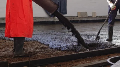 Workers pour and level a concrete floor screed in an industrial building Stock Footage 170998914