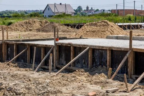 Workers pour cement to create a solid foundation for a new house in a devel.. Stock Photos