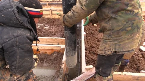 Workers pour concrete pump into the formwork of the foundation at construction Stock Footage 57319570