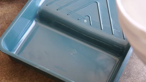 Workers pour the gray paint onto the tray before doing the painting. Stock Footage 129279642