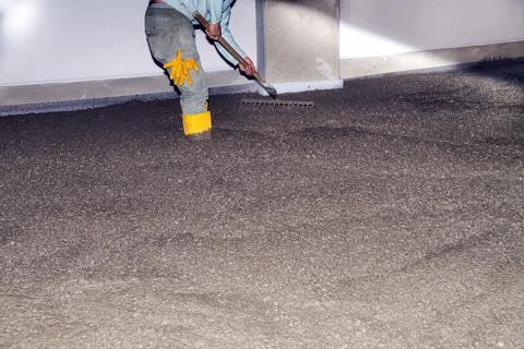 Workers pour mortar onto the floor to level it Stock Photos