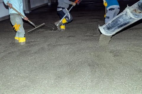 Workers pour mortar onto the floor to level it Stock Photos
