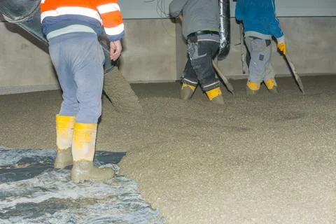 Workers pour mortar onto the floor to level it Stock Photos