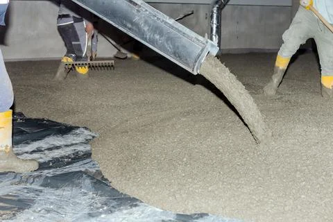 Workers pour mortar onto the floor to level it Stock Photos