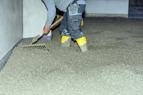 Workers pour mortar onto the floor to level it Stock Photos
