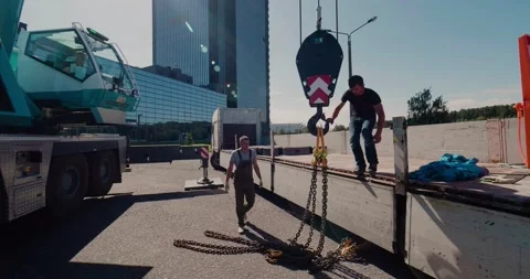 Workers prepare to attach the load to a construction crane using a hook Stock Footage 136842688