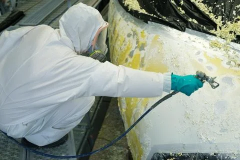 Workers in protective gear spray paint the aircraft during maintenance in the Stock Photos