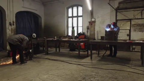 The workers in protective masks welding and grinding metal parts Vídeo Stock 225769130