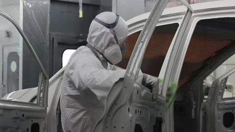 Workers in protective suits and respirators wipe the car body on the conveyor Stock Footage 122335706