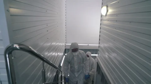 Workers in protective suits walk through the factory Stock Footage 145695878