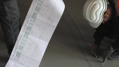Workers reading architectural sketches and marking measures on the floor. 스톡 동영상 99972885