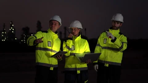 Workers in reflective jackets and helmets are talking to each other at night Stock-Footage 340083498