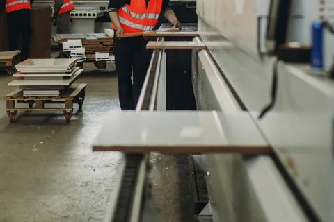 Workers in reflective vests efficiently managing large sheets of material i.. Stock Photos