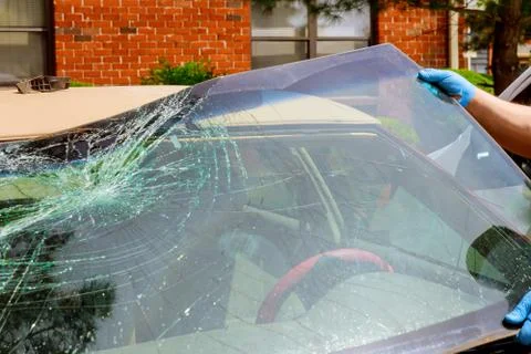 Workers remove crashed windshield of a car in auto service Stock-Fotos