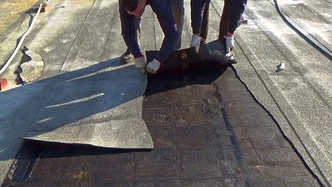 Workers remove the damaged bituminous layer from the flat roof of a building Vídeo Stock 105880342