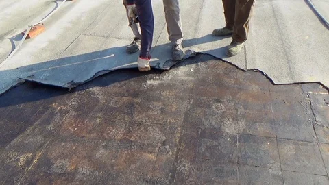 Workers remove the damaged bituminous layer from the flat roof of a building Stock-Footage 105880504