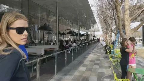 Workers removing tree lights while people enjoy drinks outdoors in urban park 動画素材 233522763