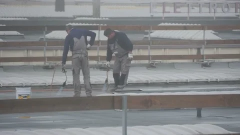 Workers on the roof working with fire under rain Stock Footage 145471151