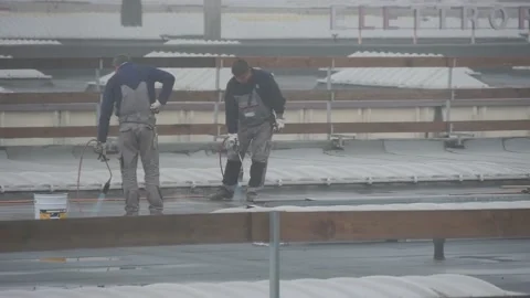 Workers on the roof working with fire under rain Stock Footage 145471158