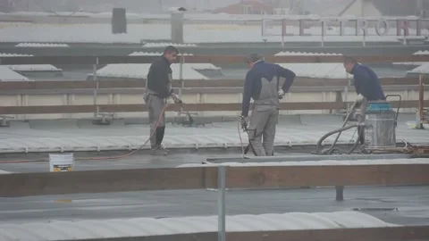 Workers on the roof working with fire under rain Stock Footage 145471192