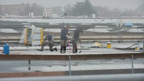Workers on the roof working with fire under rain Stock Footage 145471194