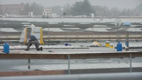 Workers on the roof working with fire under rain Stock Footage 145471224