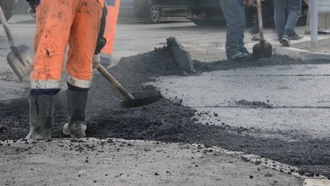 Workers in rubber boots pave the asphalt Stock Footage