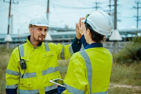 Workers in safety gear collaborating at a construction site during a cloudy d Foto stock