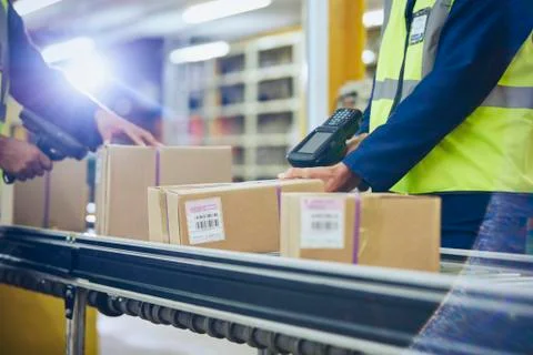 Workers scanning and processing boxes on conveyor belt in distribution warehouse Stock Photos