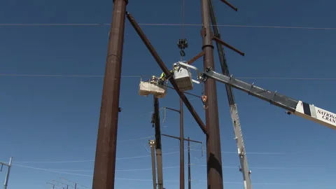 Workers secure a brace between two erected giant power poles, 4K. Stock Footage 244491591
