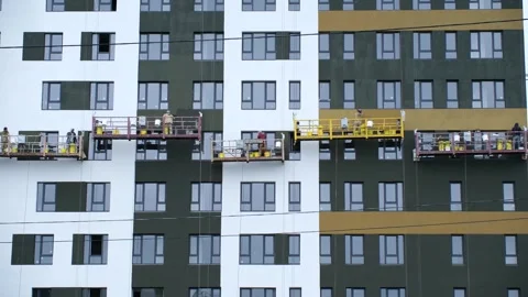 Workers securely stands on high lift near high-rise building Stock Footage 283684930
