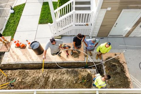 Workers seen from above after digging a trench to replace a broken pipe in .. Stock Photos
