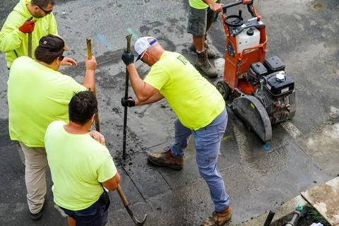 Workers seen from above cutting a hole in an asphalt street Stock Photos