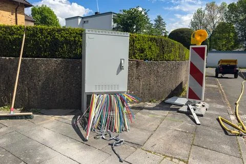 Workers set up cables near a utility box in a parking lot Stock Photos