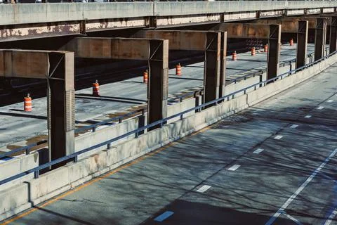 Workers set up construction on a highway overpass with orange traffic cones m Stock Photos