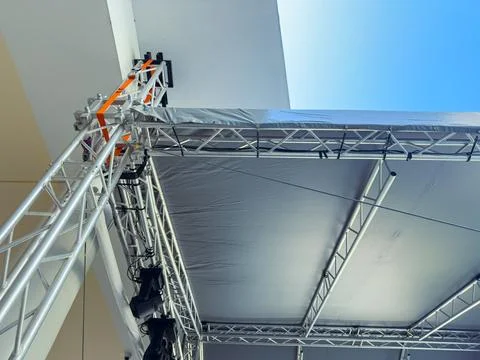 Workers set up a stage structure for an outdoor event at a venue under a cl.. Stock Photos