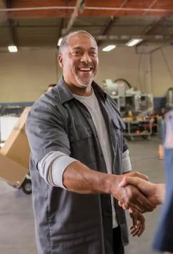 Workers shaking hands in warehouse 스톡 사진