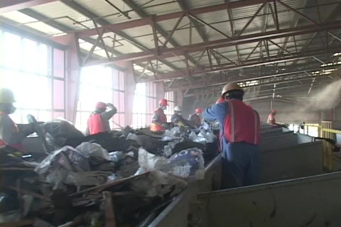 Workers sort garbage from a conveyor belt at a recycling plant. 库存影片 341068