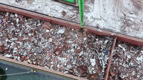 Workers sort metal recycling at a dockside facility in the afternoon sunlight Stock Footage 337906549